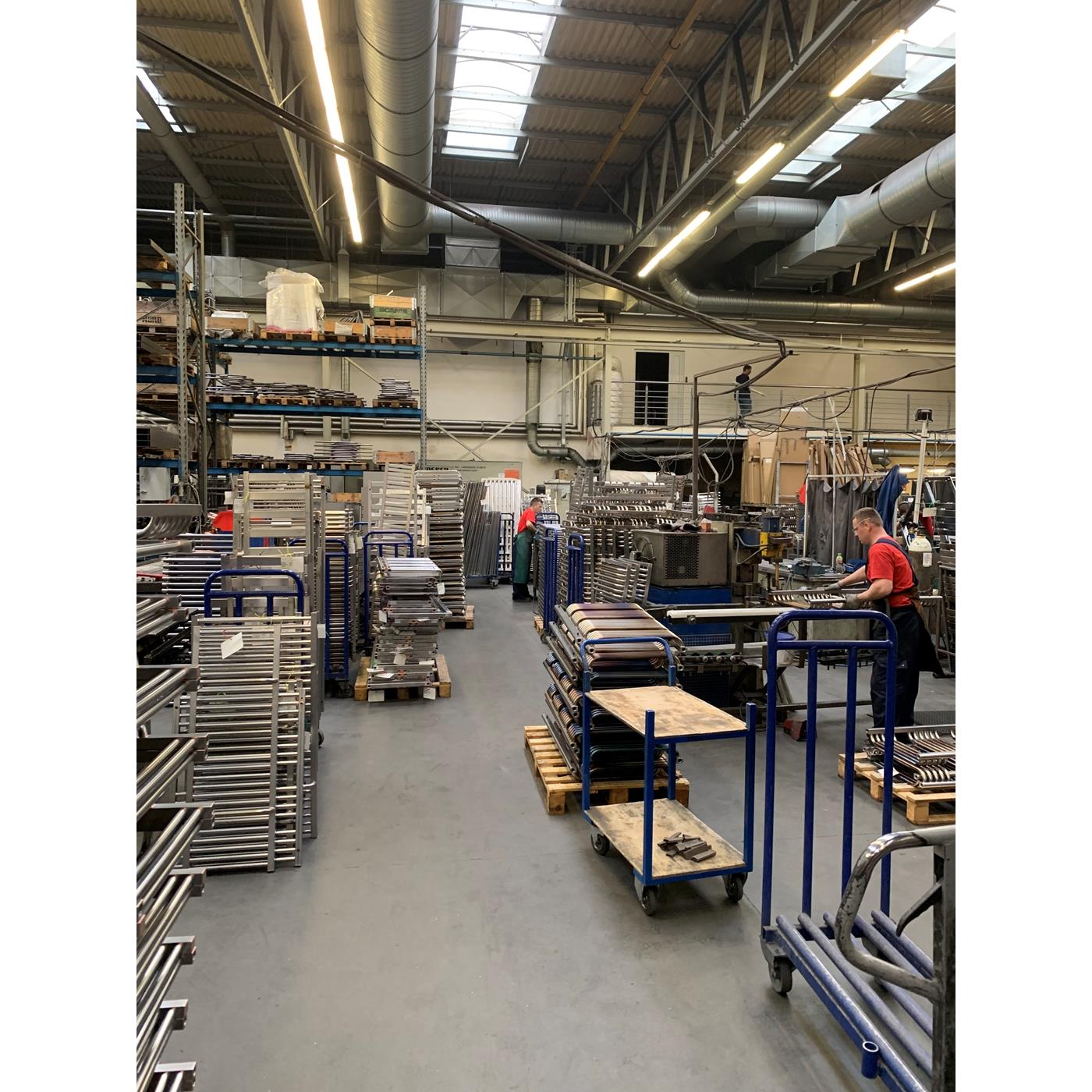 Produktionshalle mit Heizkörpern und Mitarbeitern bei der Fertigung elektrischer Badheizkörper
